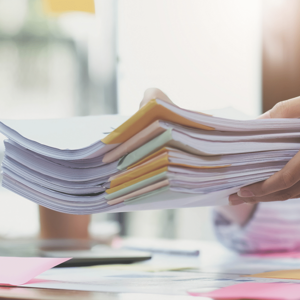 A person holds a large stack of papers with colorful tabs, conveying a busy office environment.