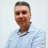 Man in blue shirt with bright background smiling in a professional photo.