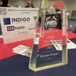 A crystal award engraved with "STEM Innovator of the Year 2025" is displayed on a table.